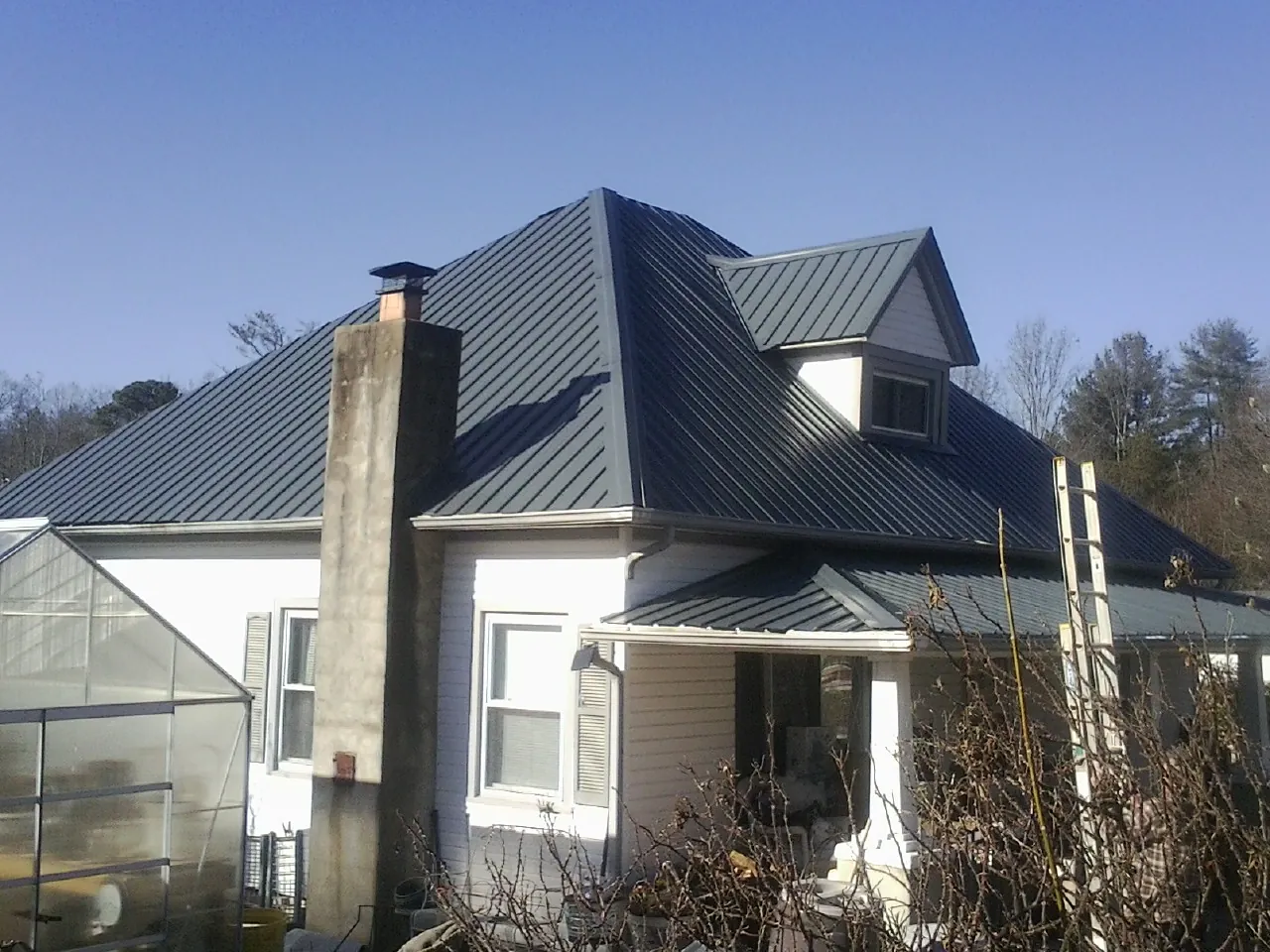 Dark blue standing seam metal roof on a white farmhouse with dormer — Slate & Tile Roof Repair by Roofing Brothers in Drayden