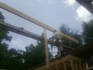 Carpenter setting a ridge beam over a new addition frame — Ice Dam Removal by Roofing Brothers in Drayden