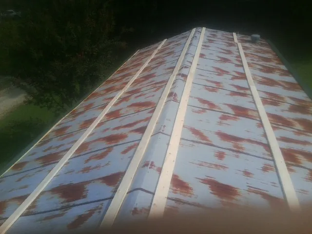 Rusted metal roof panels with new wood purlins before replacement — Storm Damage Roof Repair in Drayden by Roofing Brothers