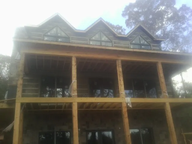 Dormers and porch framing on a large log home under construction — Roof Coating work by our crew in Drayden